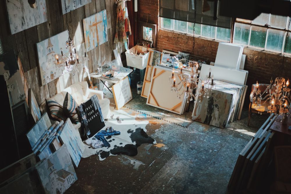 Top-down view of an art studio featuring vibrant paintings and assorted art materials, illustrating a creative environment.