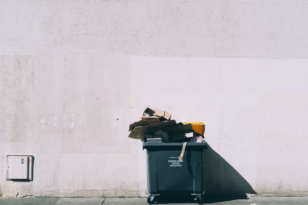 A trash can positioned beside a wall, representing outdoor junk removal services in San Jose, CA.
